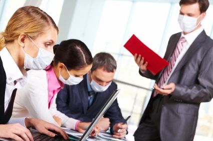 Serious businesswoman in protective mask looking at screen of laptop in working environment