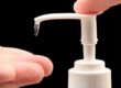 Man helping himself to a squirt of hand sanitizer, close up of bottle and hands