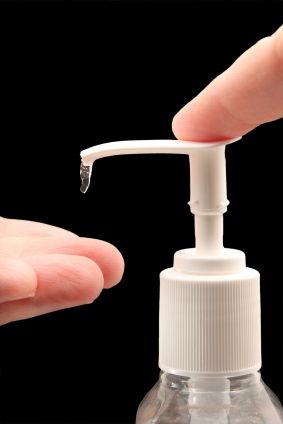 Man helping himself to a squirt of hand sanitizer, close up of bottle and hands