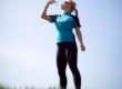 Woman taking a break and drinking water during running outdoors.