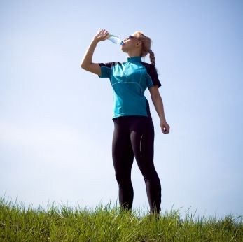 Woman taking a break and drinking water during running outdoors.