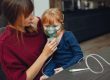 Mother helps daughter with asthma therapy, wearing a mask for inhalation