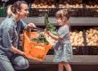 pregnant mother choosing pesticide free organic vegetables with young daughter at grocery store