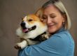 Senior woman tenderly holding a small pet dog - Tresaderm for dogs