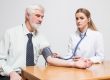 female physician checking high blood pressure signs of a man in his 60's