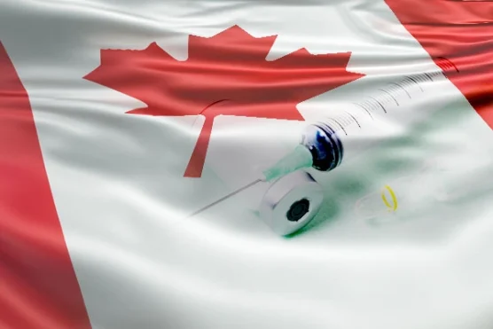 a flu shot placed on top of a Canadian flag, representing the concept of a Canadian flu shot