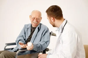 A senior man in a wheelchair smiling while discussing medication with a doctor, illustrating a supportive conversation about stopping Eliquis.