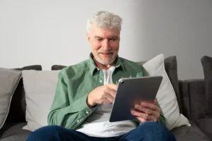 Older man smiling while using a tablet at home, researching safe options for buying amoxicillin from Mexico online.