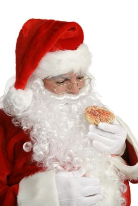 Santa considers whether or not to eat a Christmas cookie. Isolated.